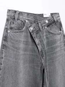 Détail d'un jean large gris avec une taille asymétrique à double boutonnage