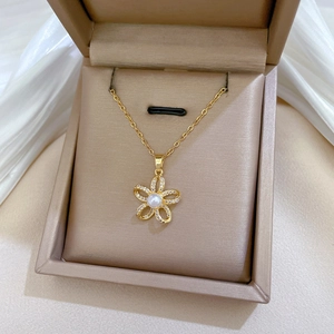 Macro detail of gold flower pendant with pearl and rhinestones in jewelry box