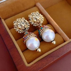 Detail of lion head earring with colorful crystals and round pearl on velvet