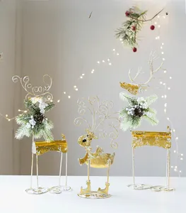 Three metal Christmas reindeer statues with pine needles and pinecones on a white tabletop