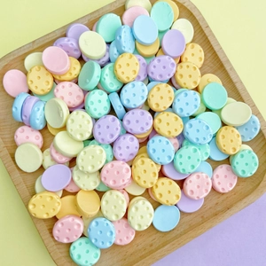 Close-up of colorful resin candy charms with polka dots in a wooden tray for DIY crafts