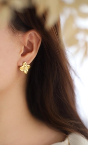 Detail of 18K gold-plated irregular metal flower earring worn by a model in close-up