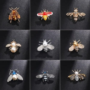 Collection of nine unique honey bee brooches with pearls and crystals on dark background