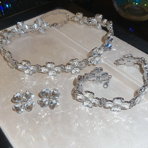 Detailed close-up of a silver four-leaf clover jewelry set featuring sparkling crystals