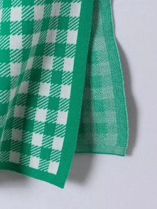Detail view of the green and white houndstooth knit fabric texture and stitching quality