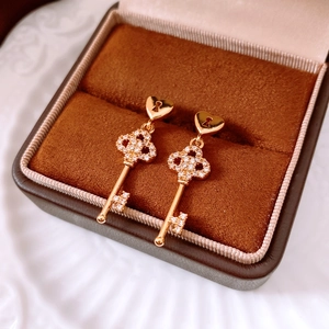 Detailed macro view of 18k gold plated key earrings with pavé white zircon stones