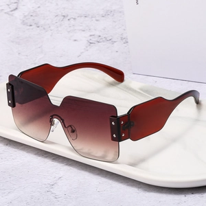 Fashionable oversized square rimless sunglasses with red-brown gradient lenses on marble