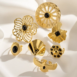 Detailed set of seven vintage gold-finish rings with black gemstone accents on white silk