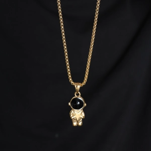 Detailed close-up of a golden astronaut pendant holding a star on a sleek black background