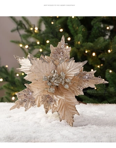 Champagne gold sequin poinsettia flower on white snow with festive Christmas tree lights