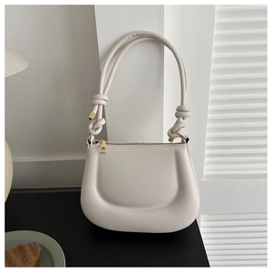Detail of off-white crossbody bag with U-shaped quilted texture and decorative knotted strap