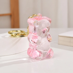 Détail d'un porte-clés ours en acrylique rose avec chaîne dorée pour sacs à dos
