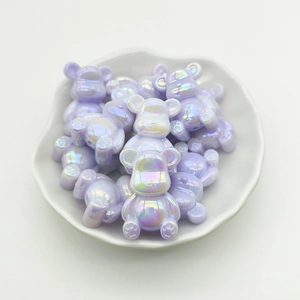 Macro shot of purple gradient bear-shaped beads in a white decorative plate for DIY crafts