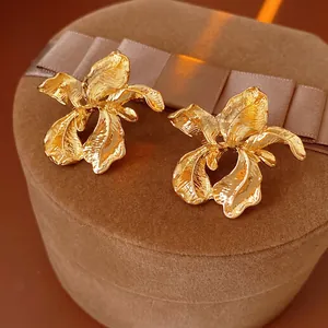 Golden irregular flower earrings on brown velvet jewelry box with high-gloss finish