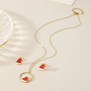 Flat lay of gold necklace and stud earrings set with red and white enamel Santa hat charms