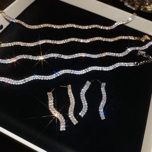 Macro shot of wavy diamond-set necklaces and earrings in gold and silver on velvet