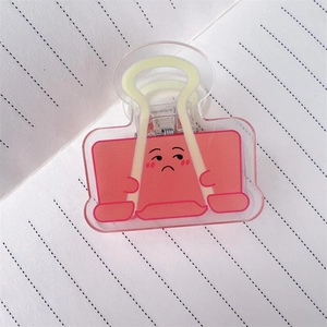 Nahaufnahme des rosa Acryl-Binder-Clips mit lustigem Gesicht auf Linienpapier