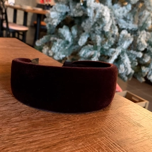 Close-up of a burgundy velvet headband with non-slip lining on a wooden background