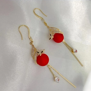 Detail of fox-head gold drop earrings with red frosted bead and sparkling tassels