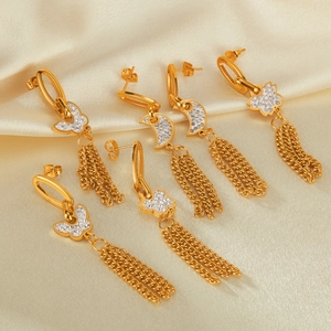Detailed macro view of gold tassel earrings with zircon butterflies and moons on silk