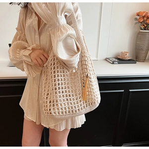 Detailed close-up of cream knit tote bag with tassel charm in a home setting