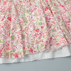 Detail of floral mini dress showing white buttons and double-layered ruffled hemline