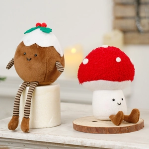 Cute Christmas mushroom and pudding plush toys on a wooden table with warm lighting