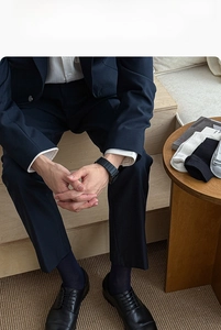 Close-up of black leather business shoes with blue suit pants and high-quality dark socks