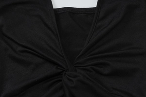 Close-up of the front twist knot detail on a black backless deep V-neck dress