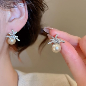 Close-up of elegant flower stud earrings with sparkling crystals and round cream pearls