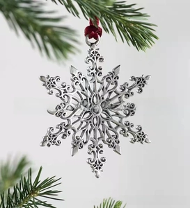 Silver metal snowflake ornament with intricate hollow pattern and red hanging string