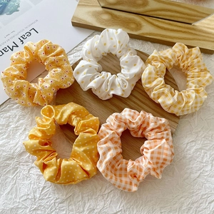 Assorted floral and checkered fabric scrunchies in vibrant yellow and orange tones