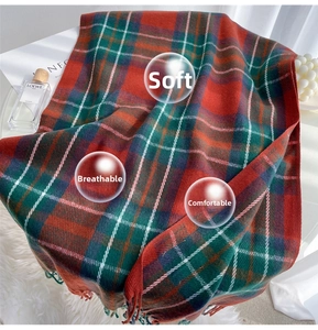 Close-up of classic red and green plaid scarf with soft fringe on a white plush rug
