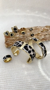 Macro detail of leopard print jewelry set with gold bracelets and earrings on wood