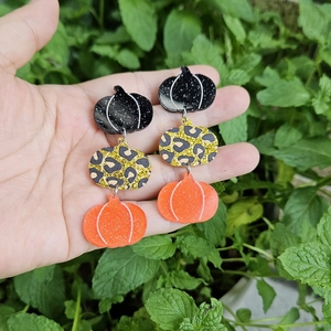 Detail of triple-stacked pumpkin earrings with black, leopard, and orange glitter finish