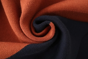 Macro shot of striped knit sweater showing burnt orange and navy blue fine texture