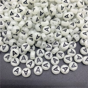 Close-up of glowing flat round acrylic letter A beads for DIY handmade jewelry crafts