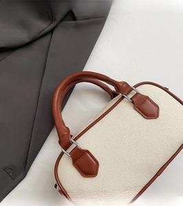 Close-up of contrast color Boston bag featuring textured fabric and brown leather straps