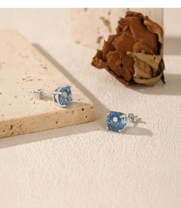 Detail of S925 sterling silver earring with a brilliant sapphire blue round-cut stone
