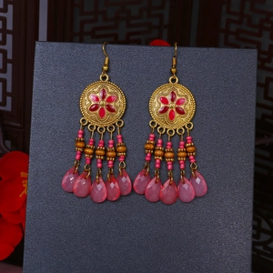 Dettaglio di orecchini boho vintage con motivi floreali rossi e pendenti rosa