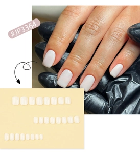 Primer plano de elegantes uñas postizas cuadradas blanco crema en mano y kit.