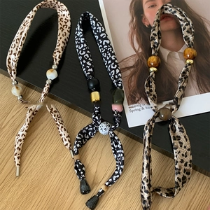 Detailed view of leopard print fabric necklaces with marble, wood, and metal beads