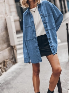 Detail of loose fit blue denim shirt jacket with large pockets and classic collar design