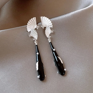 Detailaufnahme von Fächerohrringen mit schwarzem Koi-Anhänger auf Seidenhintergrund