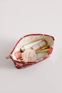 Flat lay of vintage mushroom print makeup bag with cosmetics and floral decoration