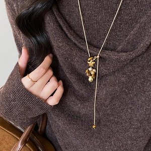 Elegante goldene Y-Halskette mit Tigerauge und Sternanhänger auf braunem Pullover