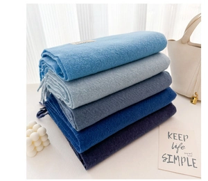 Detail of stacked blue gradient scarves with tassels in a cozy minimalist home setting