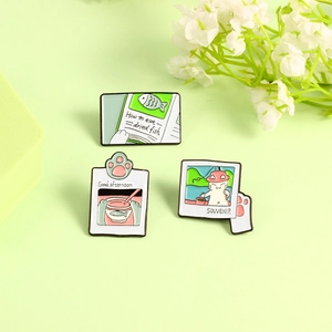 Detailed close-up of cartoon cat enamel brooch set with fish and book themes