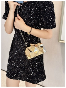 Close-up of a gold geometric faceted clutch bag with a delicate metallic chain strap