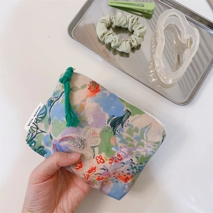 Detailed view of hand holding a small oil painting style cotton coin purse with flowers